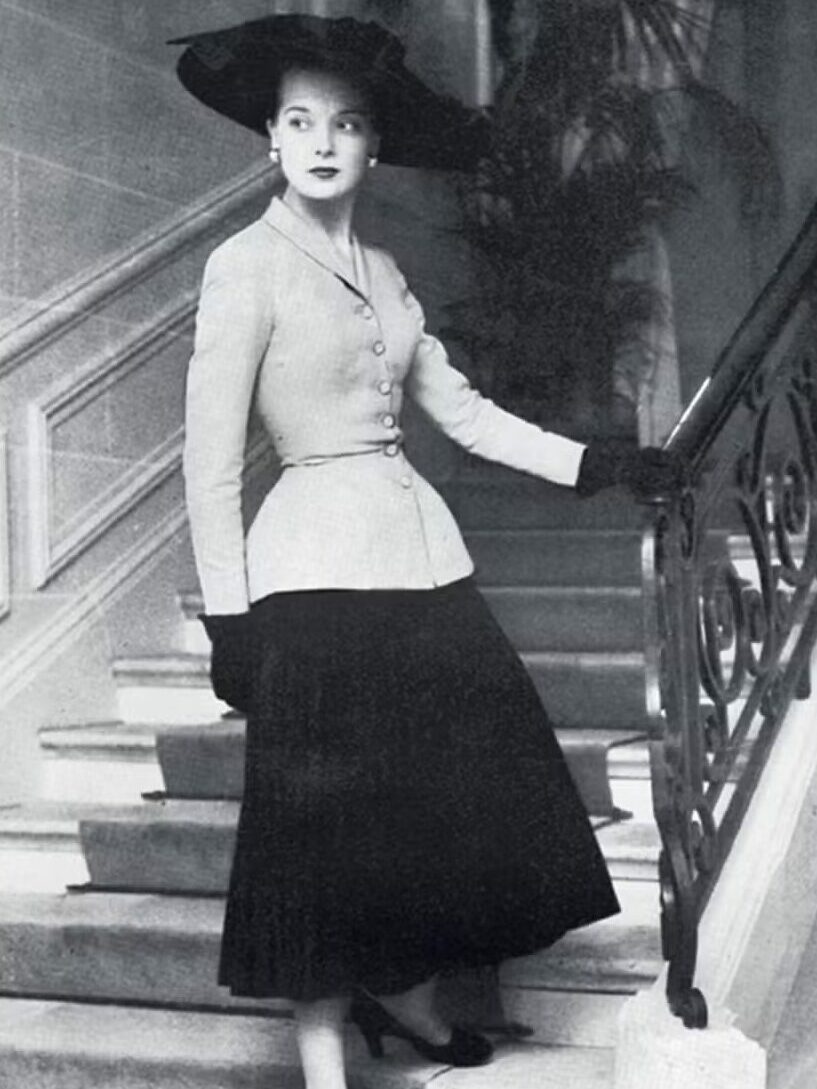 Modelo usando "The New Look" de Dior: chapéu preto, jaqueta acinturada, saia plissada longa.