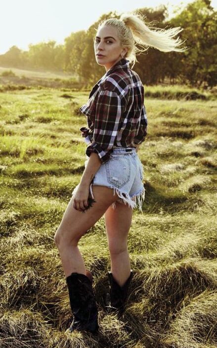 Lady Gaga veste botas country, shorts jeans e camisa de flanela.
