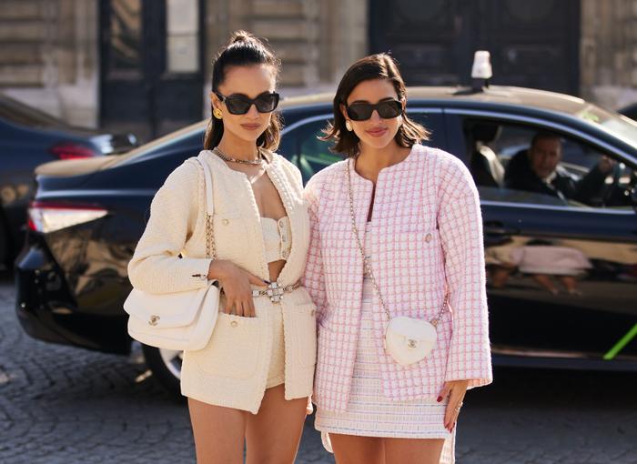 2 mulheres são fotografadas na Fashion Week de Paris, usando conjuntos clássicos Chanel.